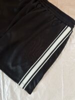 Shorts atletici neri con strisce bianche, tessuto leggero e comodo per sport e casual.