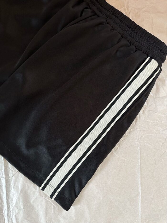 Shorts atletici neri con strisce bianche, tessuto leggero e comodo per sport e casual.