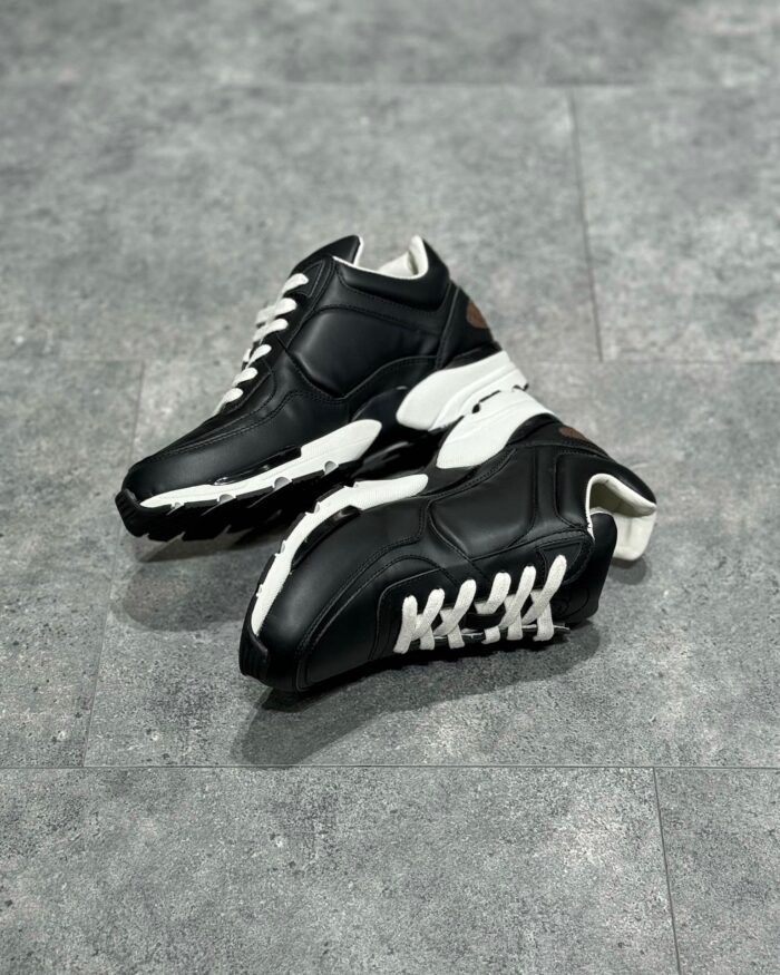 Scarpe sportive nere e bianche moderne con suola antiscivolo e design resistente.