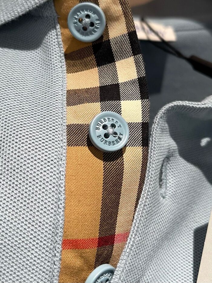 Camicia sportiva a rete grigia con dettagli a quadri beige e bottoni blu chiaro.