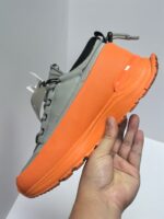 Sneaker moderna con suola arancione vivace, tessuto traspirante e design innovativo urbano.
