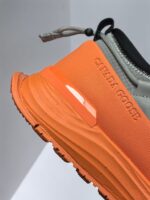 Sneaker sportiva grigia e arancione, comoda, resistente, con logo Canada Goose e design moderno.