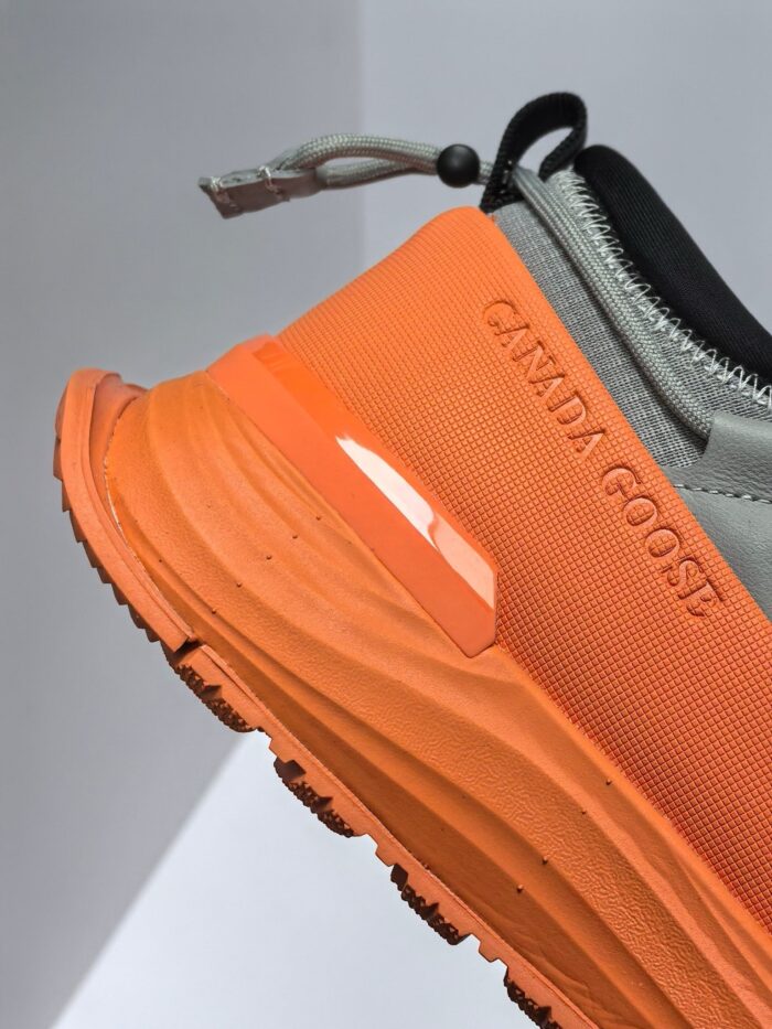 Sneaker sportiva grigia e arancione, comoda, resistente, con logo Canada Goose e design moderno.