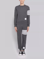 Completo sportivo grigio con strisce bianche e sneakers nere, stile athleisure casual e trendy.