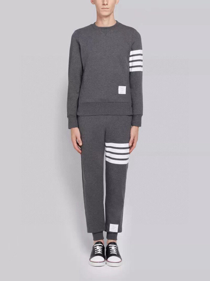 Completo sportivo grigio con strisce bianche e sneakers nere, stile athleisure casual e trendy.
