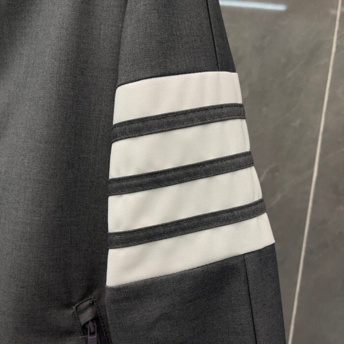 Manica di giacca sportiva grigia con strisce bianche, stile e sporty design moderno.