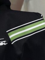 Maglietta nera con strisce verdi e bianche sulla spalla e logo ricamato elegante.
