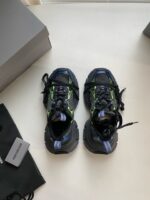 Scarpe sportive nere con dettagli verdi e blu, suola ammortizzata e design moderno.