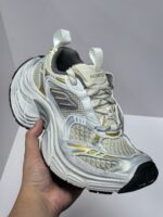 Scarpa sportiva bianca con dettagli riflettenti, suola antiscivolo e design moderno.
