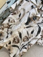 Elegant floral fabric with beige, cream, brown flowers and green leaves for spring attire.
