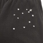 Pantaloni neri con motivo stellato, lettera S e design ispirato al cielo notturno.