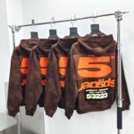 Felpe streetwear marroni con grafica numerica arancione e dettagli trendy in boutique elegante