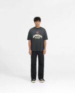 Ragazzo streetwear con T-shirt oversize, pantaloni neri e sneakers bianche in stile casual urbano.