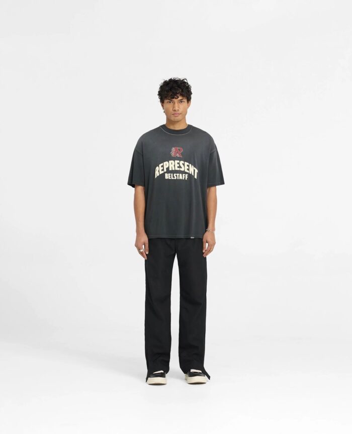 Ragazzo streetwear con T-shirt oversize, pantaloni neri e sneakers bianche in stile casual urbano.