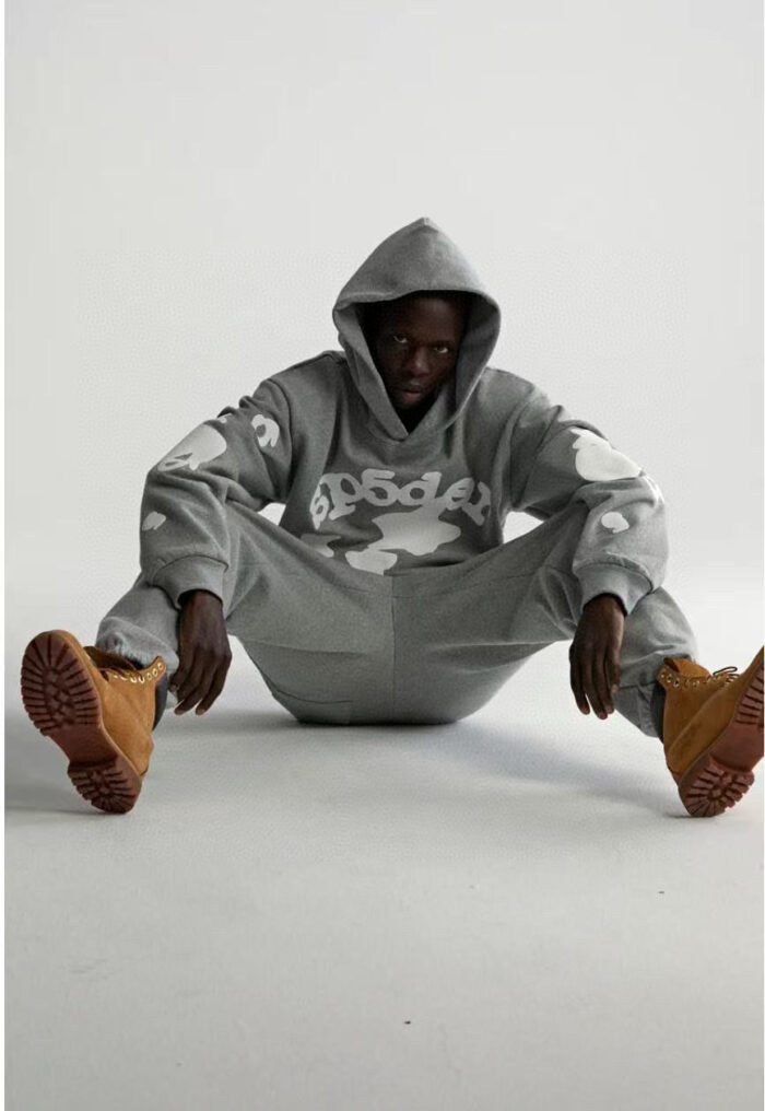 Stile streetwear casual con hoodie, pantaloni e stivaletti robusti su sfondo minimalista.