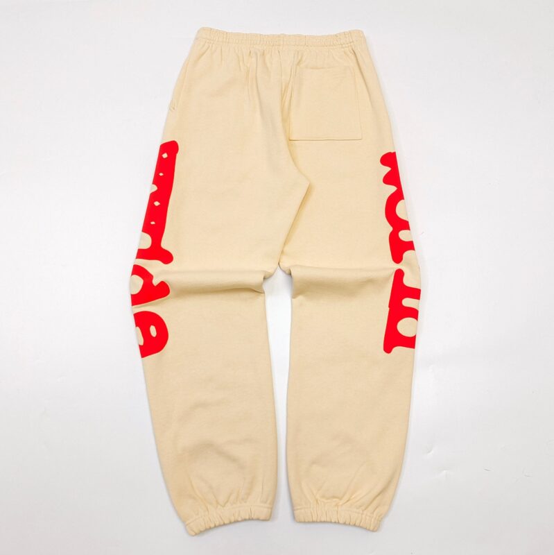 Pantaloni jogger cream con stampa rossa artistica, elastici e tasca laterale, stile streetwear.