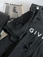 T-shirt distressed nero, rivista Jil Sander, pochette elegante, stile streetwear sofisticato.