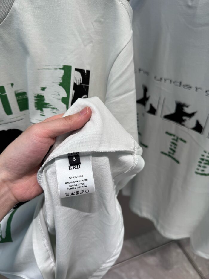 Persona che approfondisce una maglietta streetwear con design graffiti e dettagli moderni.