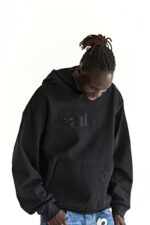 Giovane in streetwear con hoodie nero e dreadlocks, stile urbano casual e distintivo.
