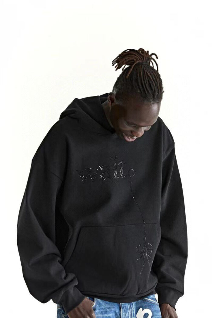 Giovane in streetwear con hoodie nero e dreadlocks, stile urbano casual e distintivo.