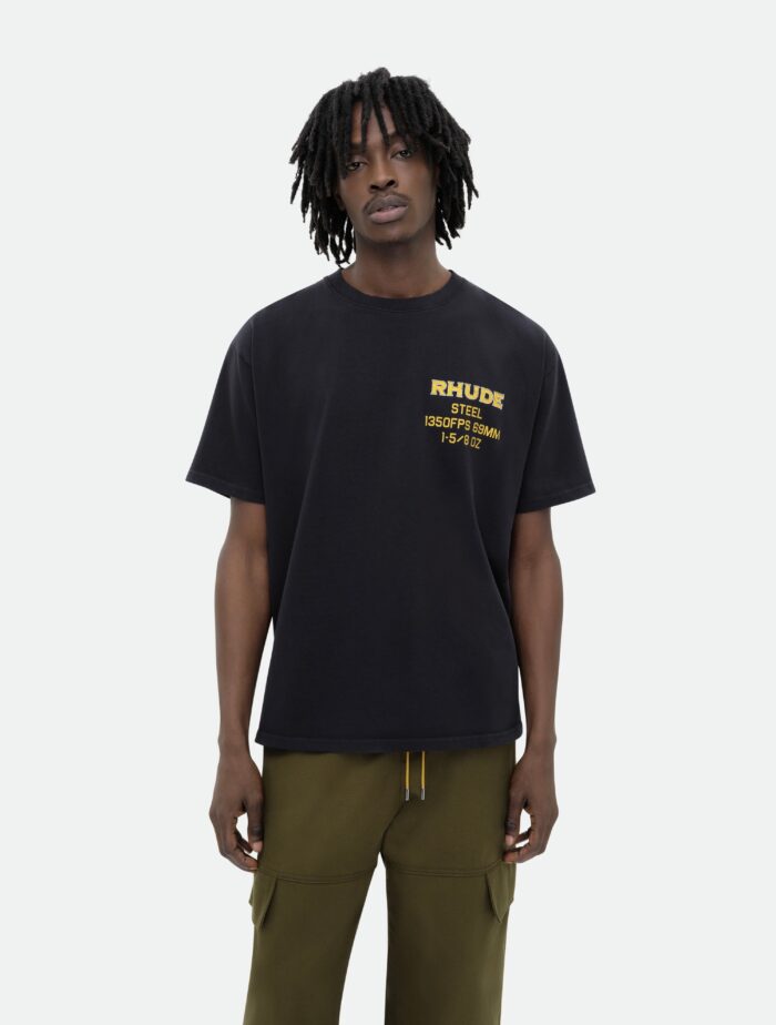 Uomo streetwear con t-shirt nera logo giallo RHUDE e pantaloni cargo oliva.