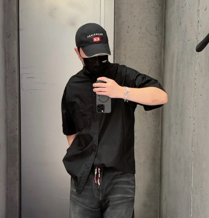 Selfie streetwear urban in stile casual con cappellino, mascherina e sfondo in cemento.