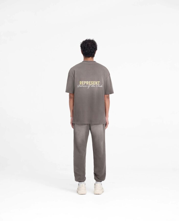 Look casual streetwear con T-shirt REPRESENT e sneakers bianche su sfondo minimalista