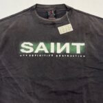 Maglietta streetwear nera con grafica SAINT e frase audace, stile urbano e moderno.
