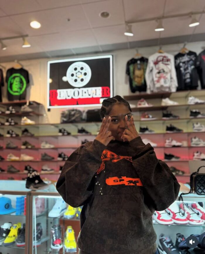Negozio di sneakers e streetwear trendy con cliente stile urban e illuminazione neon vibrante.