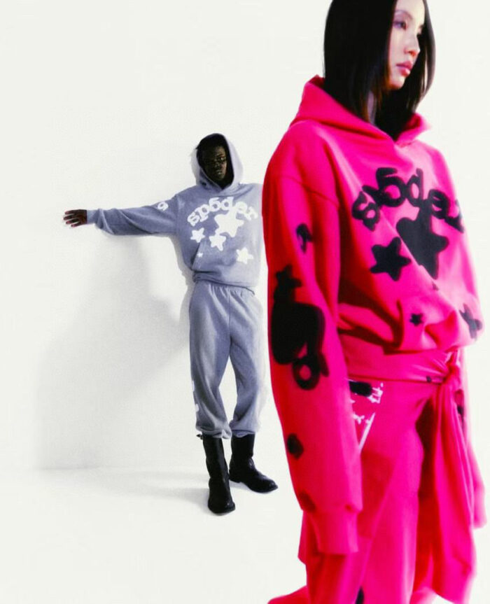 Modelli streetwear moderni con hoodie colorati e grigi in sfondo minimalista.