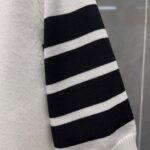 Maglione casual con manica a righe bianche e nere, stile moderno e confortevole.