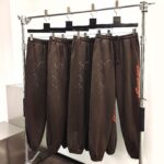 Pantaloni jogger marroni con dettagli glitter e logo in stile urbano minimalista.