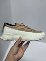 Sneaker beige e nera in suede con suola bianca, design moderno e comfort per ogni occasione.