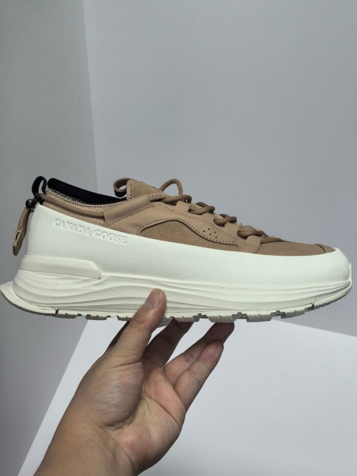Sneaker beige e nera in suede con suola bianca, design moderno e comfort per ogni occasione.