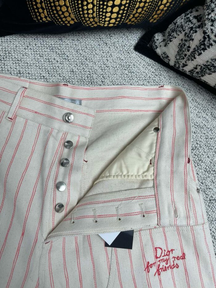 Pantaloni beige Dior con bottoni metallici, righe sottili e stile elegante e confortevole.