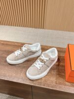 Sneakers beige in camoscio con suola bianca, stile casual e raffinato, su superficie di legno.