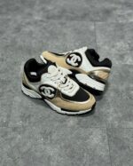 Sneakers nere e beige con logo iconico, suola chunky e design moderno e confortevole.