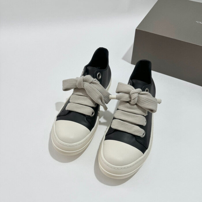 Sneaker nera elegante con lacci grigi, suola bianca, stile casual e moderno.