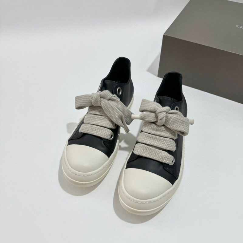 Sneaker nera elegante con lacci grigi, suola bianca, stile casual e moderno.