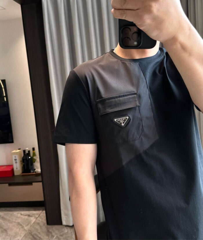 Look moderno con T-shirt nera, logo triangolare e dettagli stilosi in un ambiente elegante.