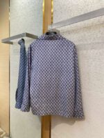 Camicia blu con fantasia geometrica, stile casual e semi-formale, esposta su portariviste minimalista.