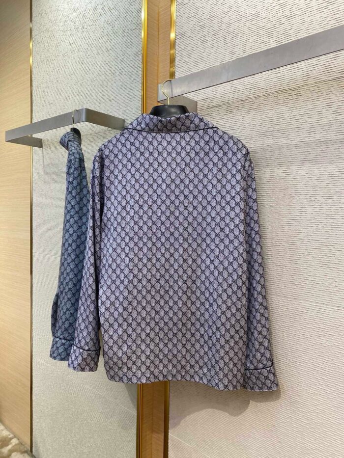 Camicia blu con fantasia geometrica, stile casual e semi-formale, esposta su portariviste minimalista.