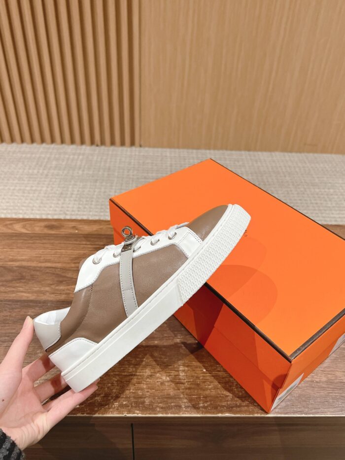 Sneaker di lusso marrone e bianco con confezione arancione, stile moderno e alta qualità.