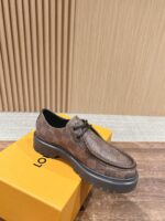 Scarpa in pelle marrone con suola nera, su scatola arancione, sfondo pannelli di legno elegante.