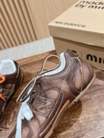 Sneakers in pelle marrone con dettagli arancio e bianco, stile elegante e comfort casual.