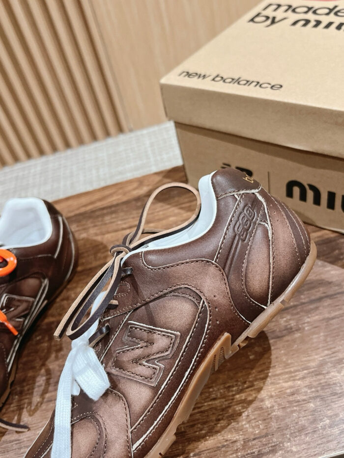 Sneakers in pelle marrone con dettagli arancio e bianco, stile elegante e comfort casual.