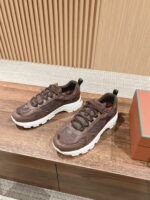 Scarpe sneakers marroni moderne con suola bianca su superficie di legno, eleganti e di tendenza.