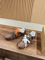 Scarpe sneakers moderne in pelle marrone con lacci colorati su superficie in legno elegante.