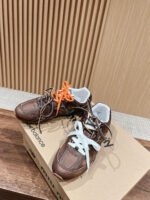 Sneakers marroni con lacci colorati su scatola New Balance, stile e comfort in ambiente elegante.