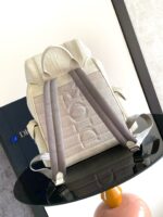 Zaino moderno color crema con spallacci grigi su tavolo lucido, stile minimalista e raffinato.